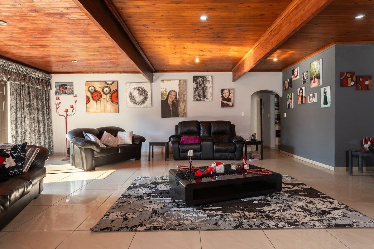 Spacious living room featuring a warm timber-clad ceiling with exposed beams, recessed lighting, and neutral tiled flooring, creating a comfortable and inviting atmosphere.