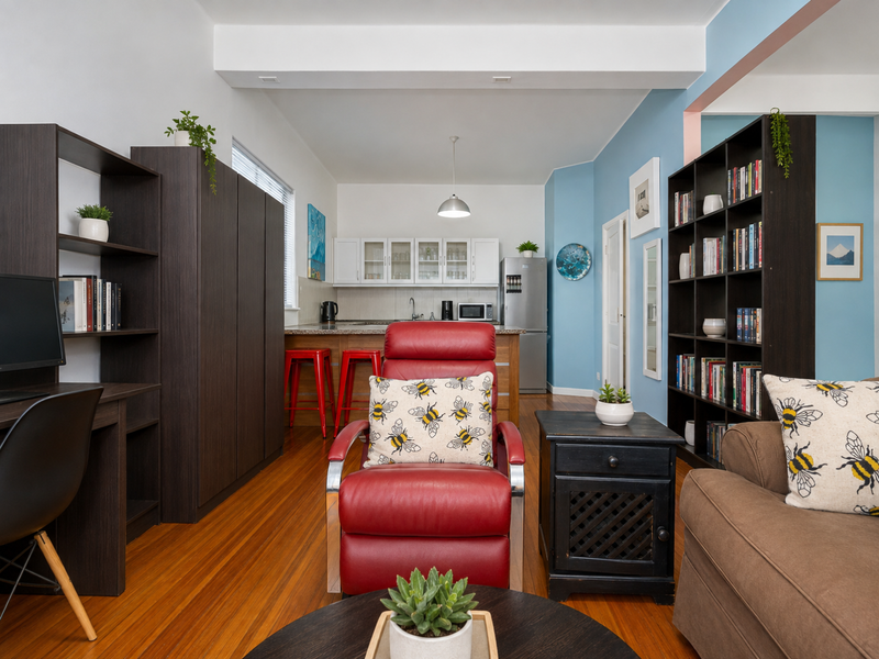 An open-plan living area featuring hardwood flooring, a functional kitchen with granite countertops, and a bright, well-maintained interior layout.