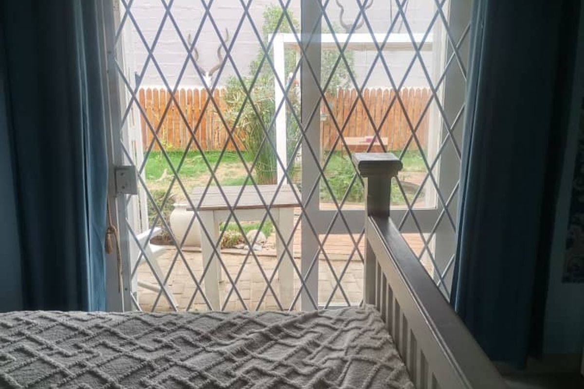 A bedroom featuring a sliding glass door with a security gate, providing direct access to a rear garden area.