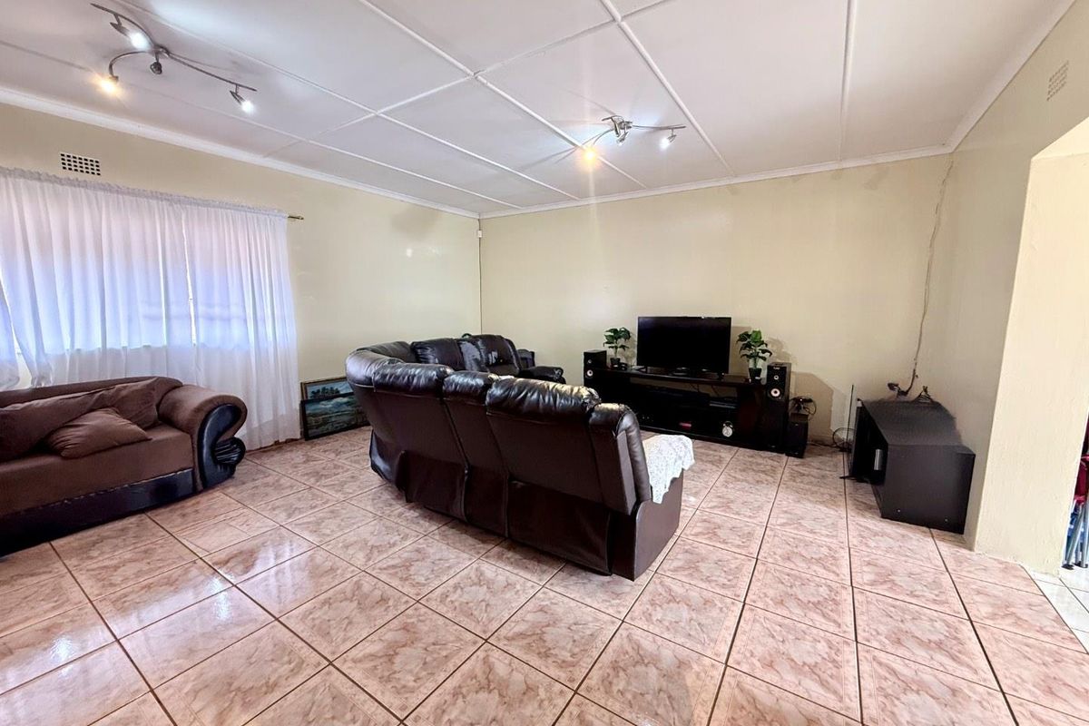Spacious living room featuring tiled flooring and ceiling-mounted track lighting, providing a functional and open area for relaxation.