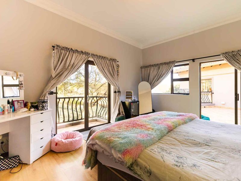 Spacious bedroom featuring laminate flooring, neutral walls, and dual sliding glass doors providing direct access to an outdoor balcony area.
