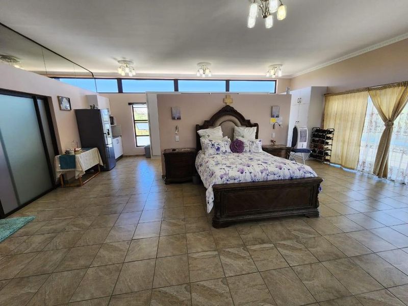 Spacious bedroom featuring tiled flooring, clerestory windows for natural light, built-in storage, and direct access to an outdoor area via sliding glass doors.
