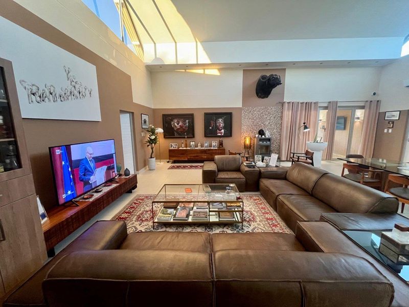 Spacious open-plan living area featuring high vaulted ceilings, a large skylight for natural light, tiled flooring, and a built-in fireplace.