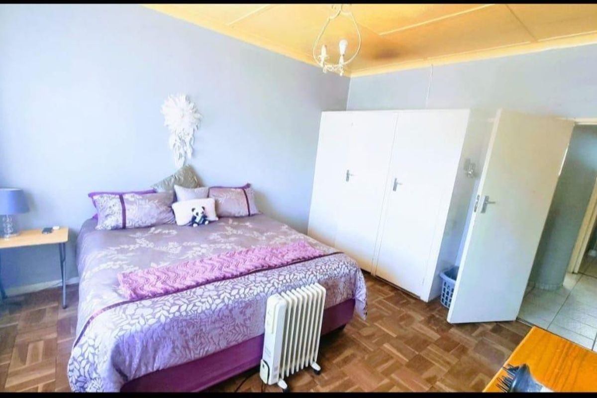 A bedroom featuring parquet flooring, built-in cupboards, and a coved ceiling, with an adjacent view into a tiled bathroom area.
