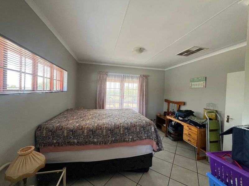 A spacious bedroom featuring tiled flooring, a ceiling vent, and a sliding glass door providing natural light and access to the exterior.