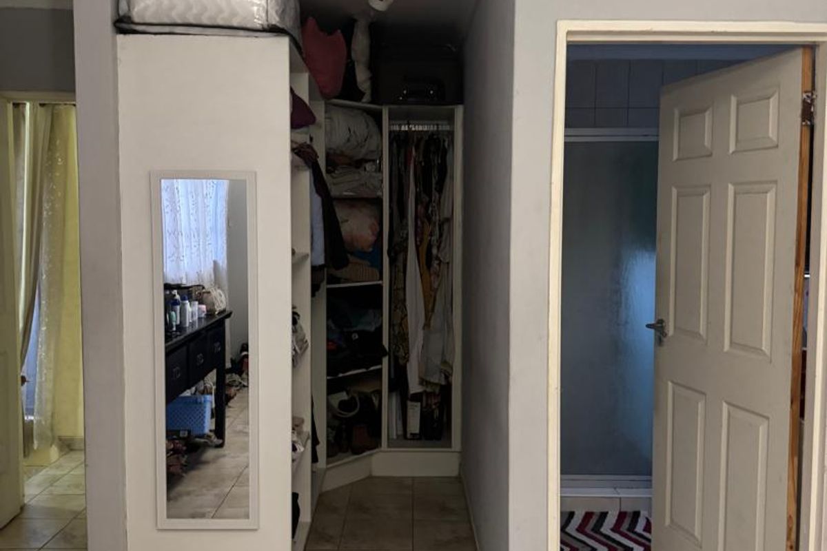 A functional hallway area featuring built-in storage cupboards and tiled flooring, providing access to adjacent rooms including a bathroom.