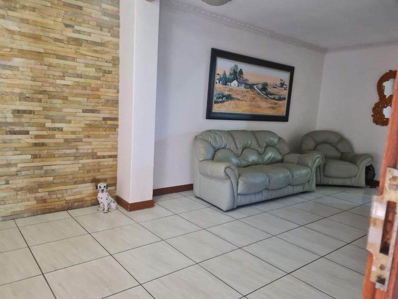 A living room featuring a textured stone accent wall, neutral tiled flooring, and decorative crown molding.