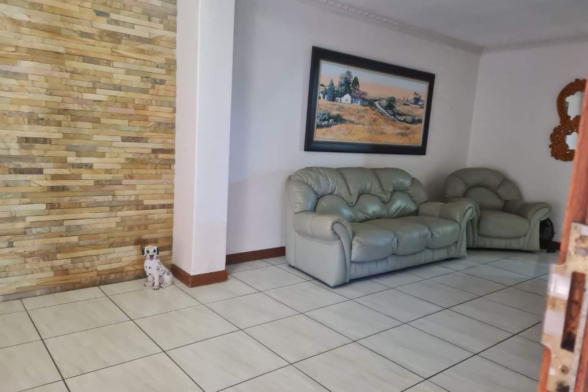 A living room featuring a textured stone accent wall, neutral tiled flooring, and decorative crown molding.