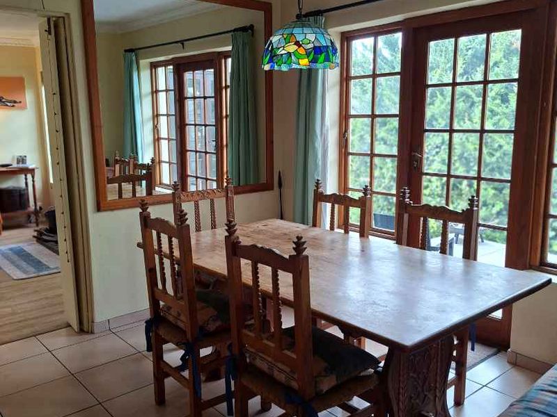 A dining room featuring tiled flooring, a large built-in wall mirror, and classic french doors that provide natural light and garden access.