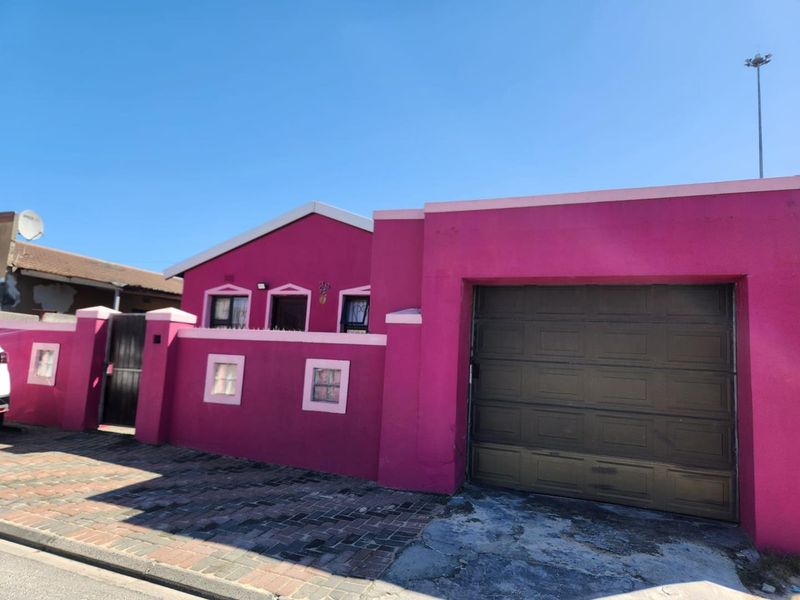 Front elevation of a residential property featuring a single garage, boundary wall, and paved driveway access.