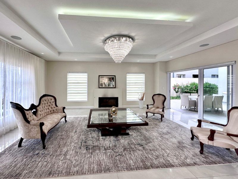 Spacious living room featuring a recessed ceiling with ambient lighting, a built-in fireplace, and large sliding glass doors opening to an outdoor patio area.