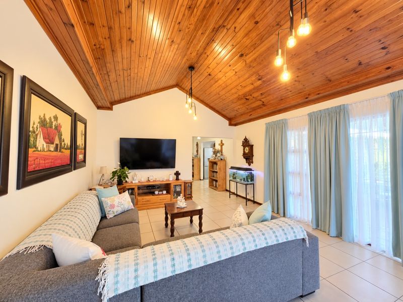 Spacious living room featuring a high vaulted timber ceiling, tiled flooring, and large sliding glass doors that provide ample natural light.