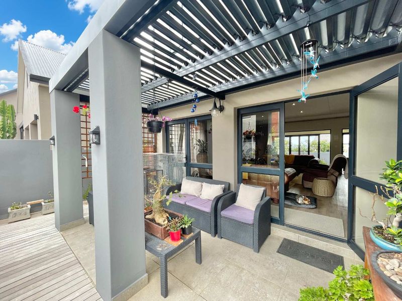 A covered patio area featuring a modern louvred roof, tiled flooring, and large sliding glass doors providing seamless access to the interior living space.