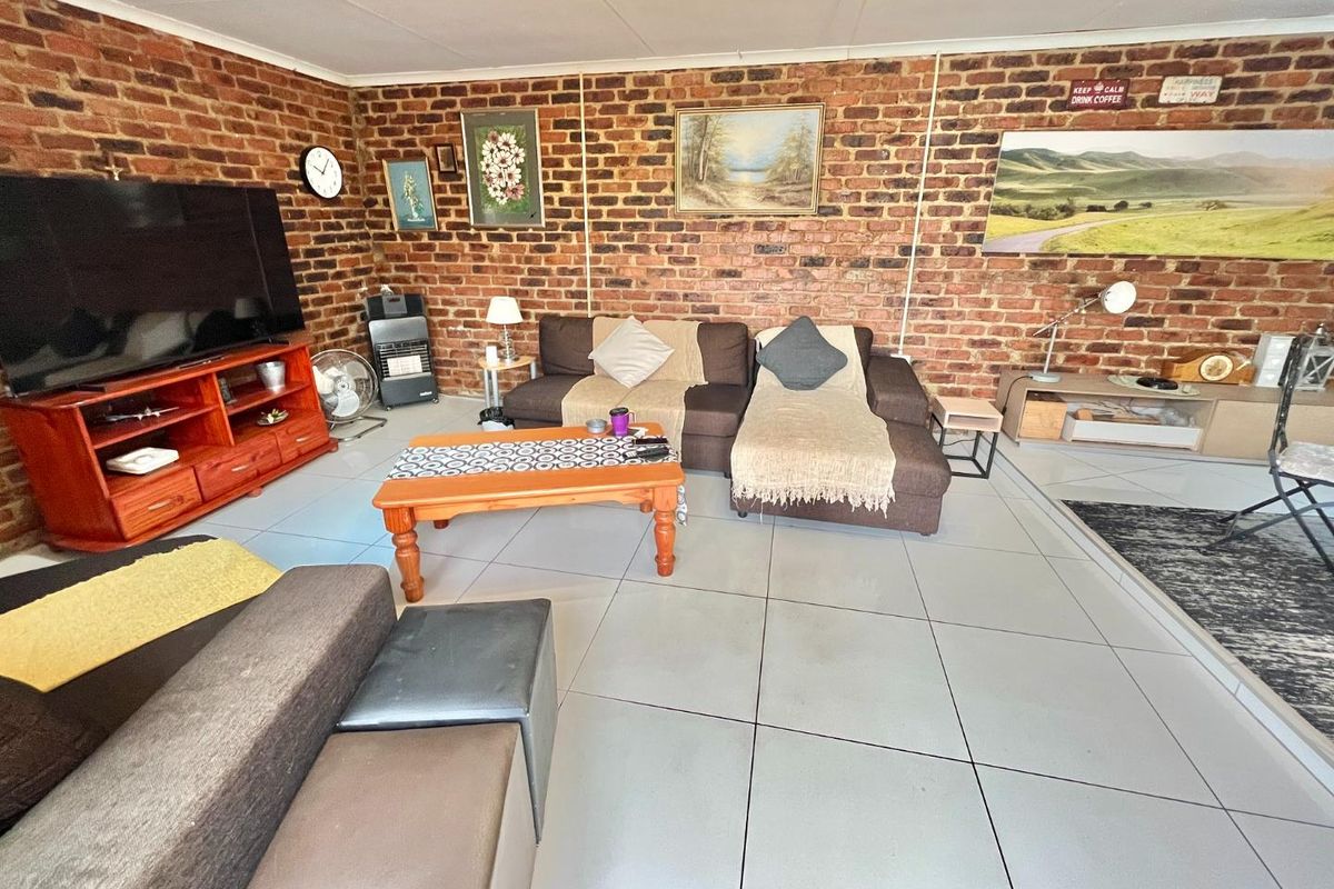 A living room featuring an exposed brick feature wall and large format floor tiles, providing a rustic yet modern foundation for the space.