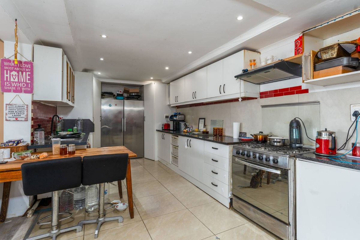 Functional kitchen featuring white cabinetry, granite countertops, a stainless steel gas stove with extractor fan, and tiled flooring.