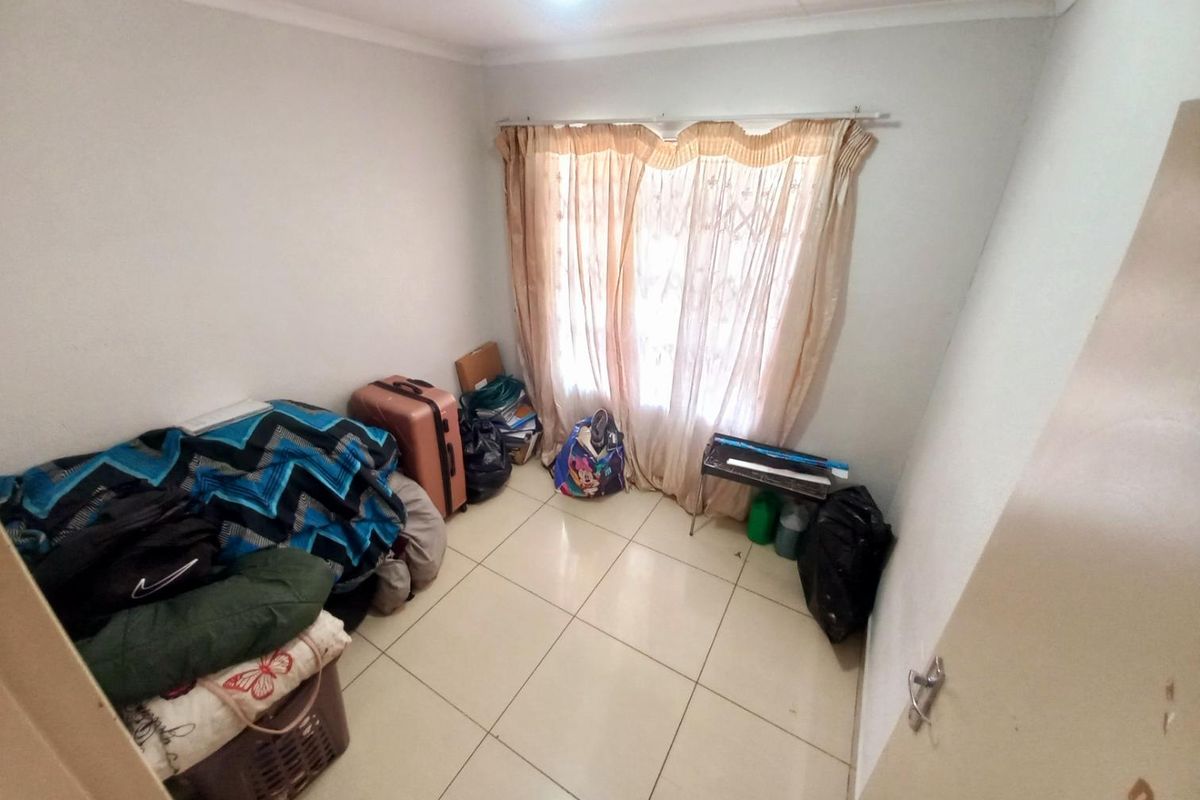 A bedroom featuring tiled flooring and a window with curtain rails, providing a functional space for rest or storage.