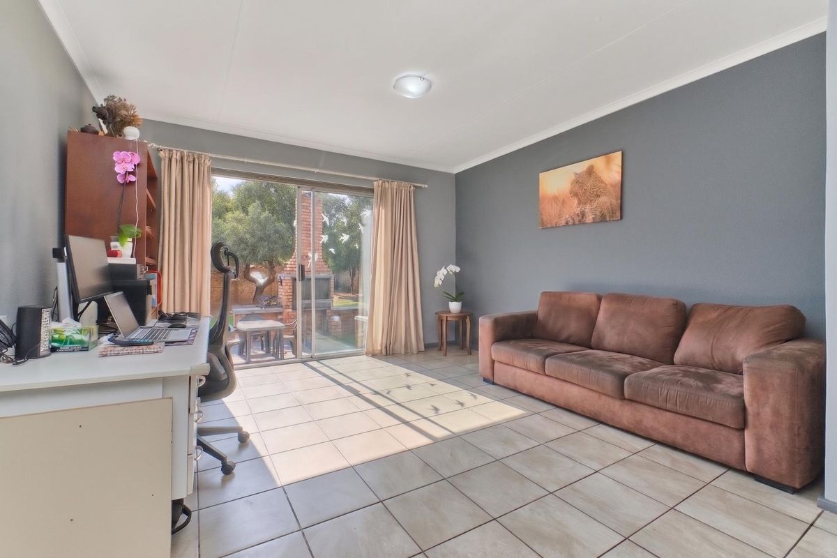 A bright living room featuring tiled flooring and large sliding glass doors that provide direct access to the outdoor patio area.