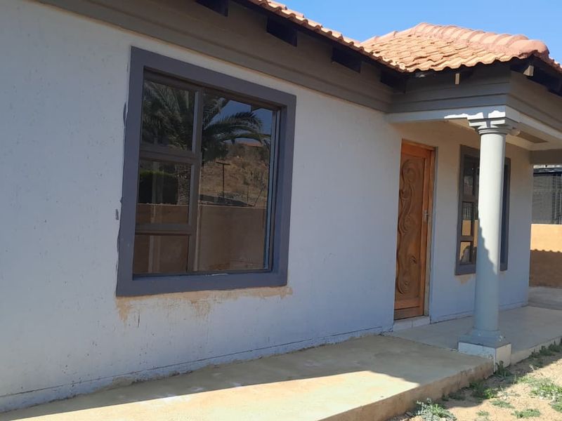 Front exterior view of the house featuring a covered porch with concrete columns, tiled roof, and wooden entrance door.
