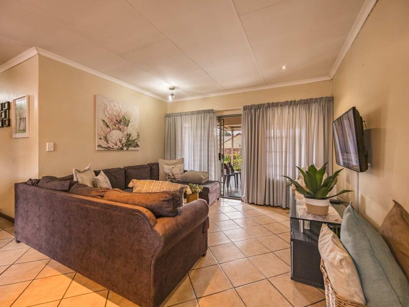 A comfortable living room featuring tiled flooring, coved ceilings, and a sliding glass door providing access to the outdoor patio area.