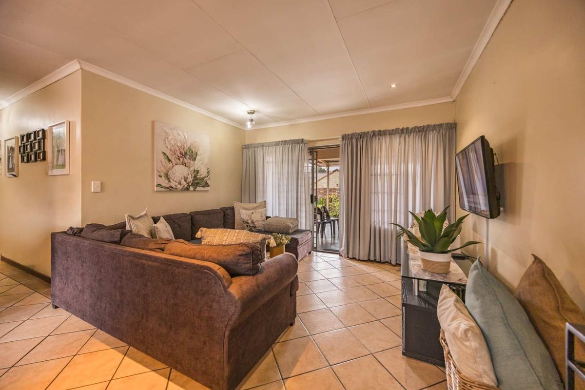 A comfortable living room featuring tiled flooring, coved ceilings, and a sliding glass door providing access to the outdoor patio area.