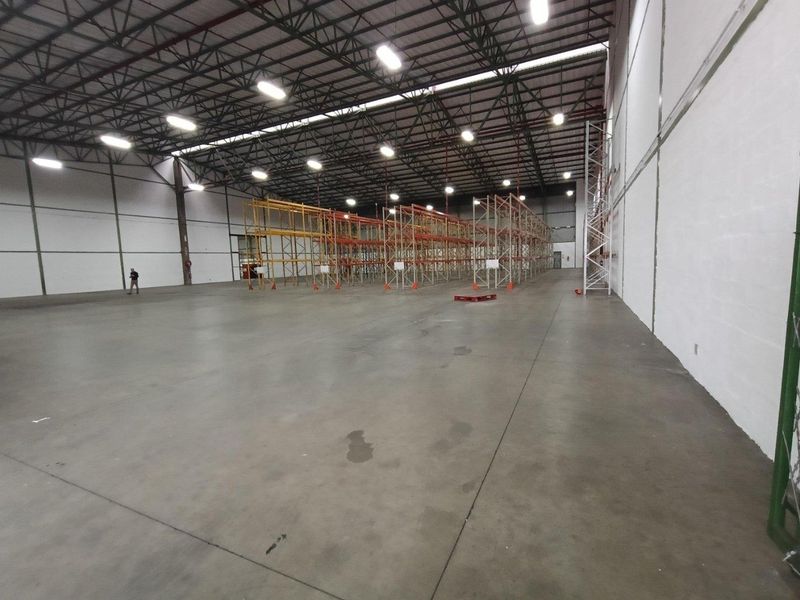 Spacious industrial warehouse featuring high-clearance ceilings, exposed steel trusses, durable concrete flooring, and integrated steel racking systems suitable for storage or logistics operations.