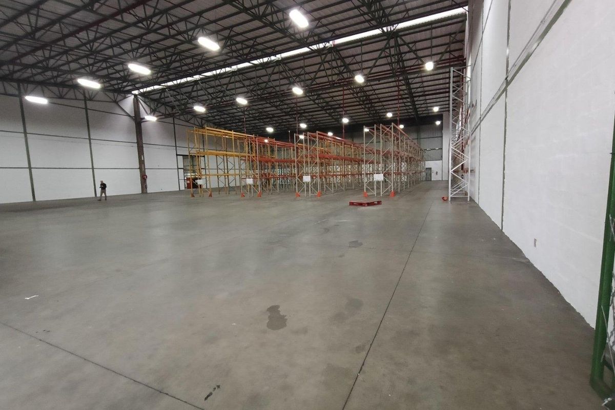 Spacious industrial warehouse featuring high-clearance ceilings, exposed steel trusses, durable concrete flooring, and integrated steel racking systems suitable for storage or logistics operations.