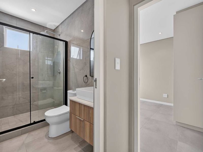 Modern bathroom featuring a walk-in shower with glass enclosure, contemporary vanity with vessel sink, and neutral floor-to-ceiling tiling.