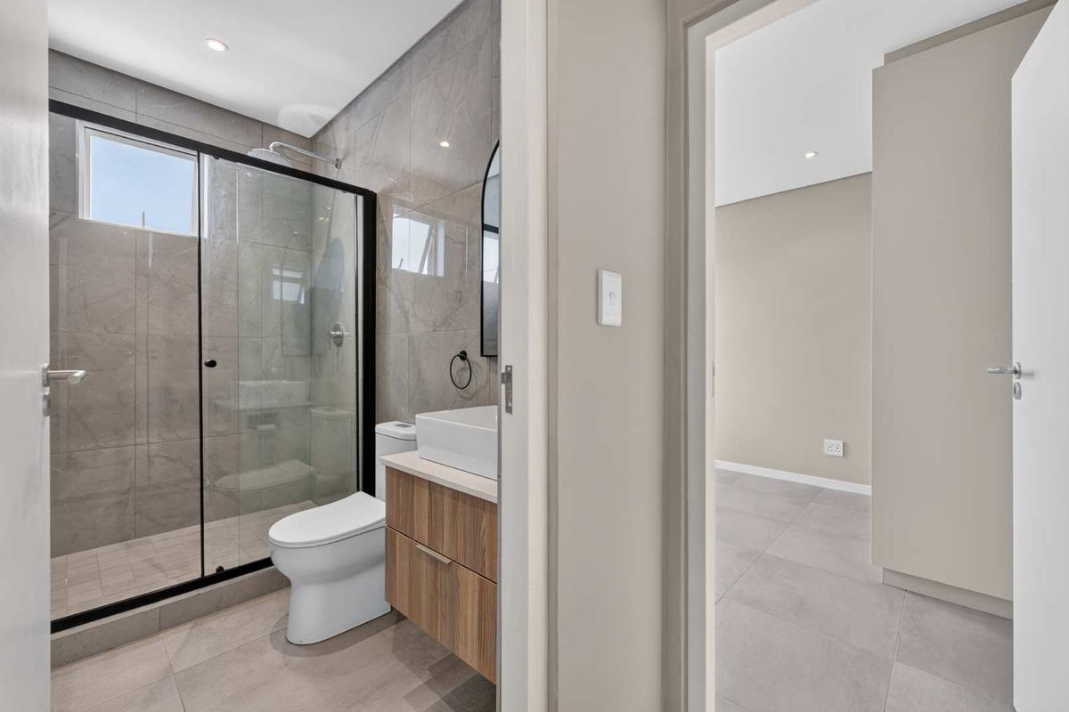 Modern bathroom featuring a walk-in shower with glass enclosure, contemporary vanity with vessel sink, and neutral floor-to-ceiling tiling.