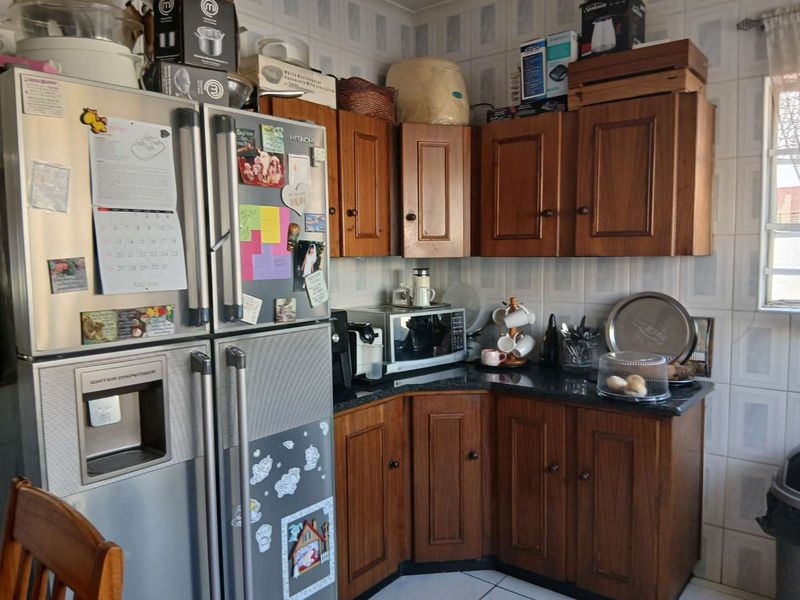 A functional kitchen featuring traditional wooden cabinetry, granite countertops, and tiled wall finishes, providing a classic and practical workspace.