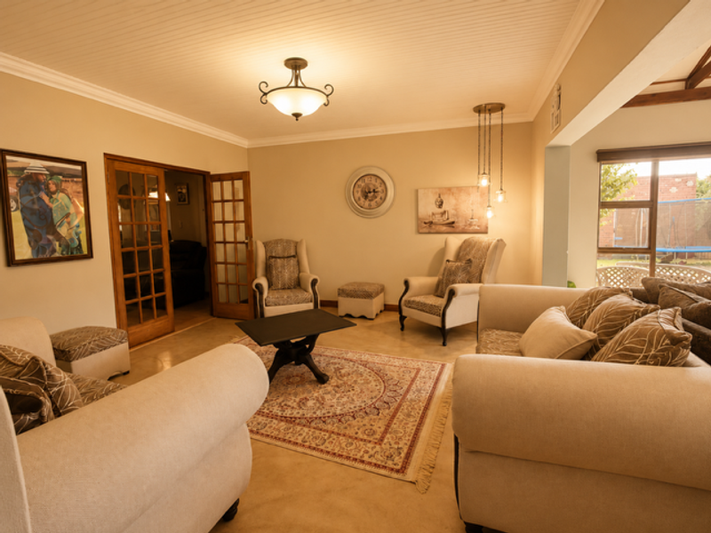 A comfortable living room featuring a beadboard ceiling, tiled flooring, and classic french doors leading to an adjacent space.