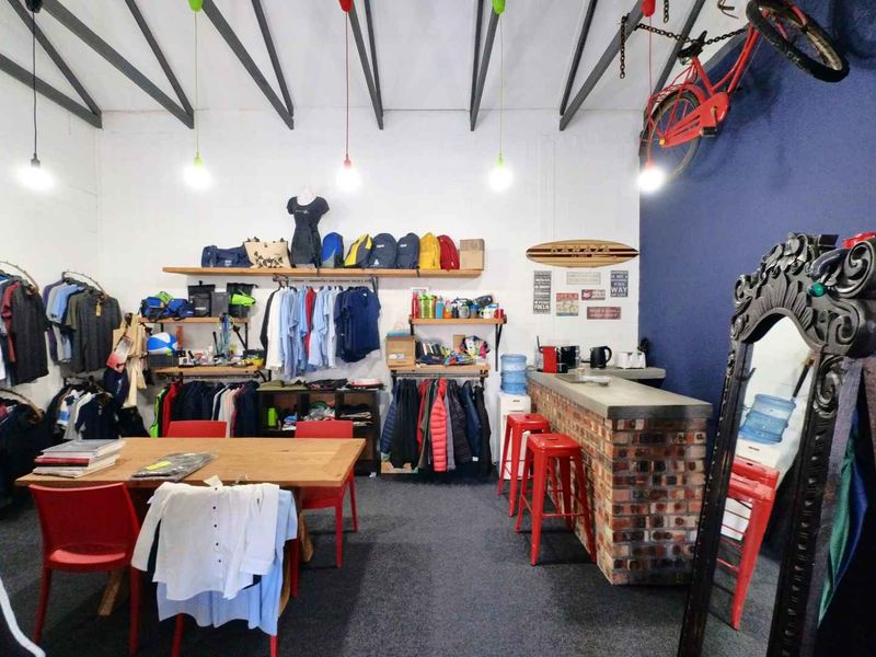 Open plan industrial space featuring exposed roof trusses, a brick bar counter, and wall-mounted shelving units.