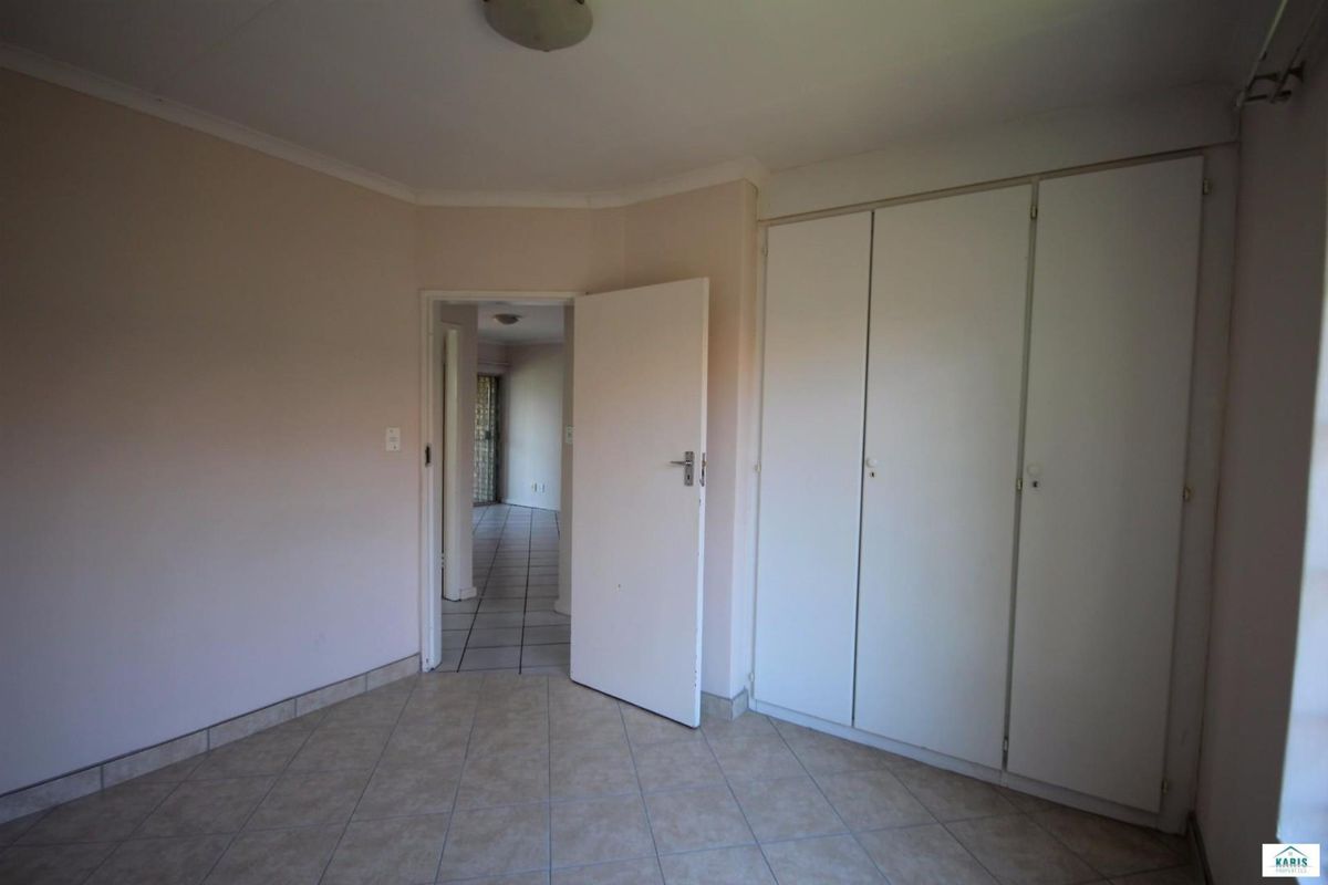 An empty bedroom featuring built-in cupboards, tiled flooring, and neutral wall finishes, offering a blank canvas for personalization.