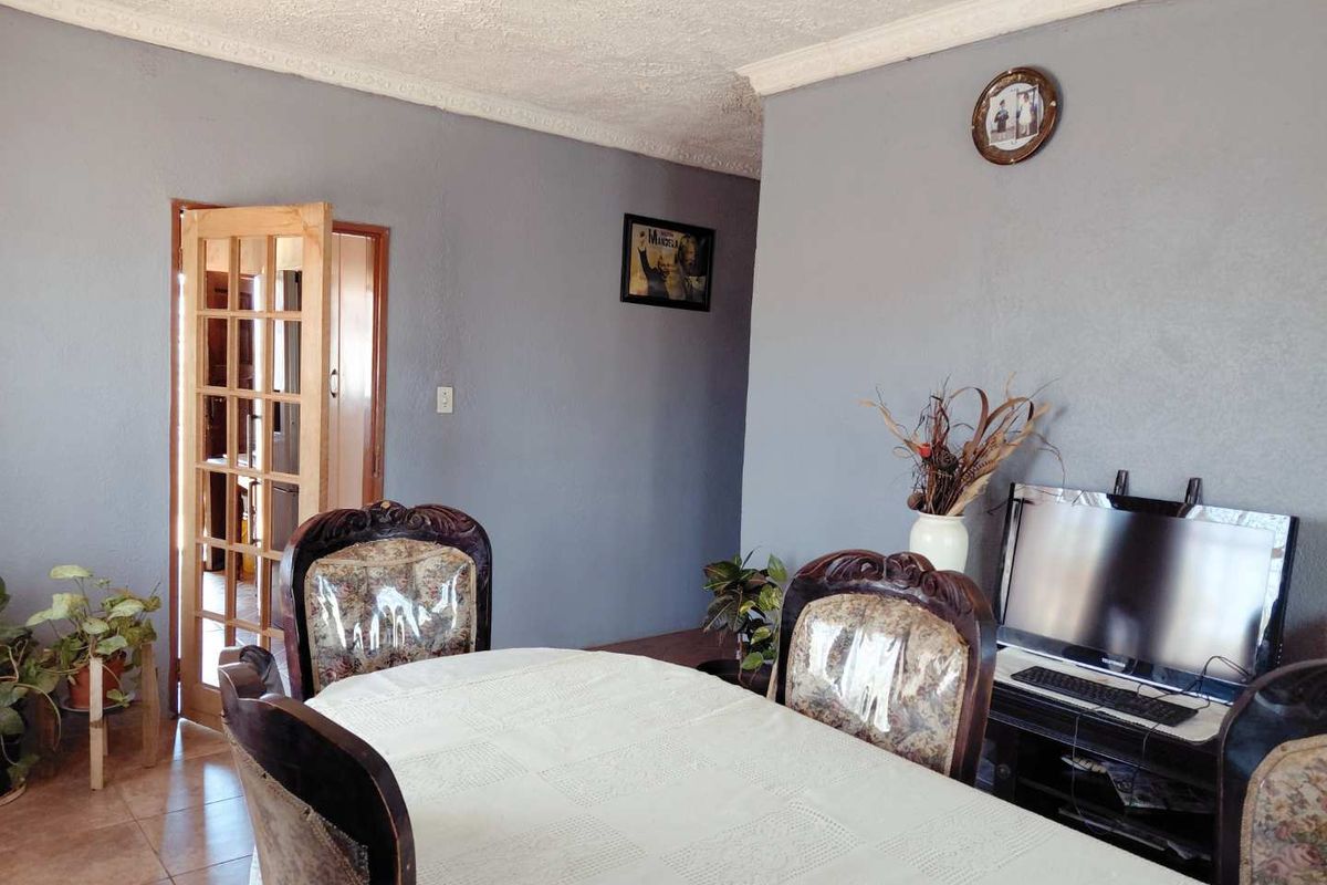 A living area featuring tiled flooring, coving, and a wooden french door leading to an adjacent room.