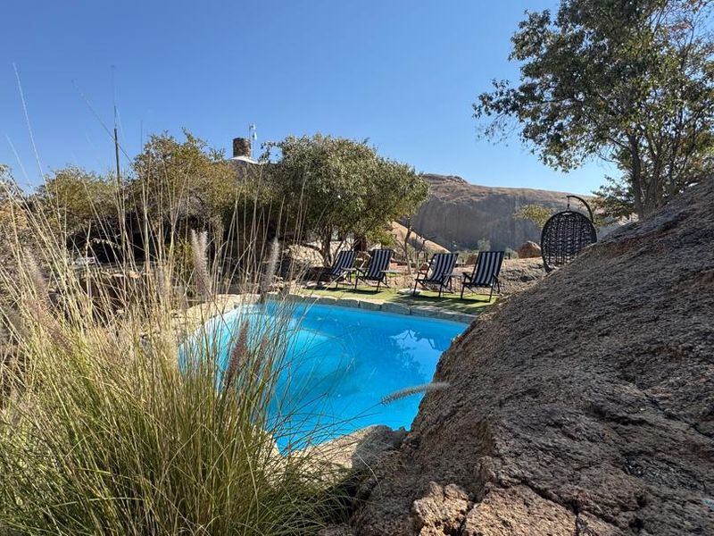 A scenic outdoor pool area integrated into a natural rocky landscape, offering a tranquil setting with views of the surrounding terrain.
