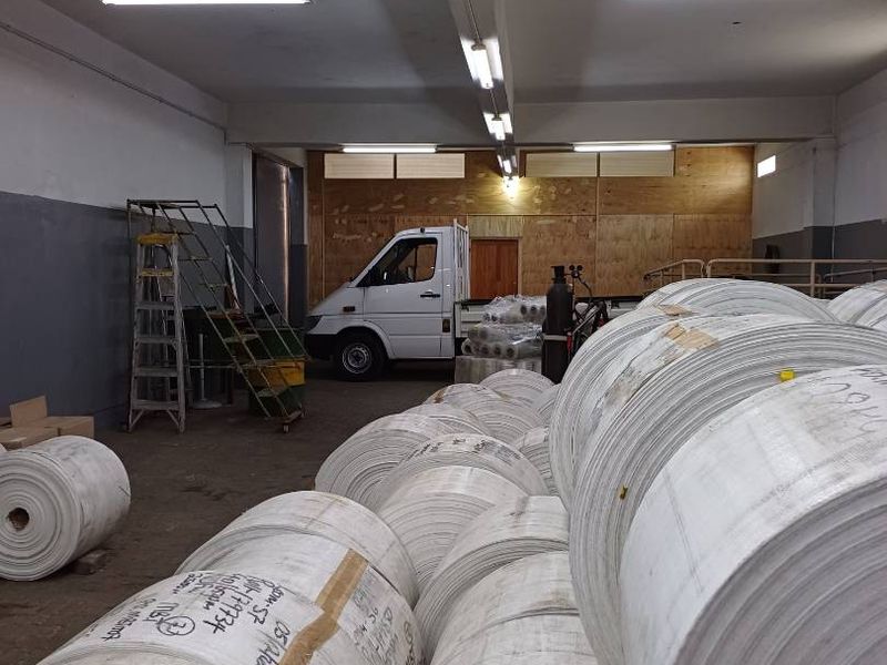 A spacious industrial utility or storage area featuring high ceilings with fluorescent lighting, suitable for warehouse operations or logistics.