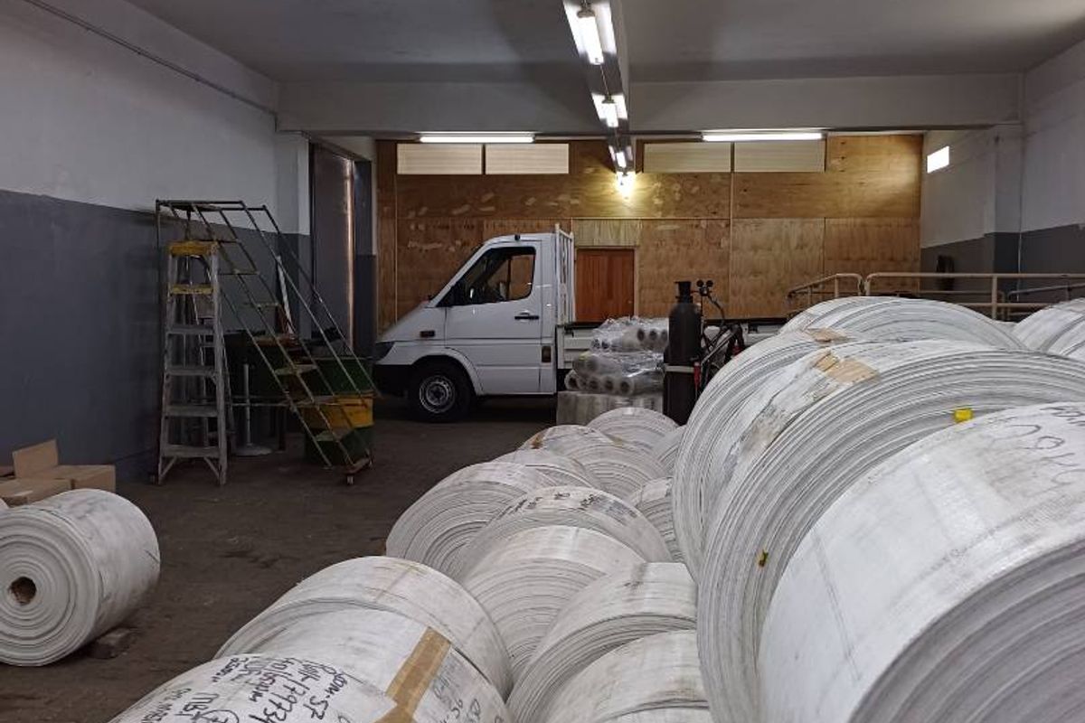 A spacious industrial utility or storage area featuring high ceilings with fluorescent lighting, suitable for warehouse operations or logistics.