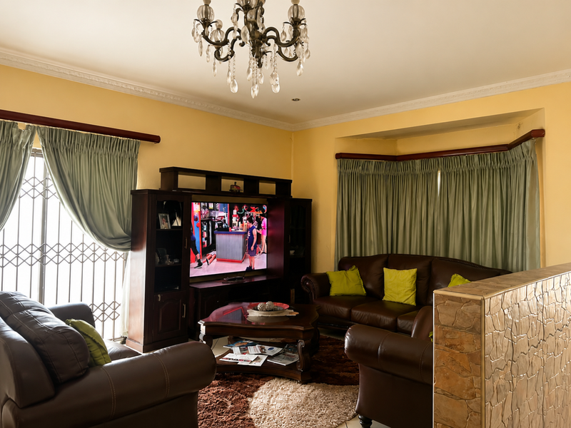 A cozy living room featuring a decorative crystal chandelier, crown molding, and a unique stone-clad half wall partition.
