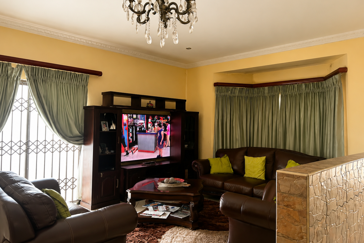 A cozy living room featuring a decorative crystal chandelier, crown molding, and a unique stone-clad half wall partition.