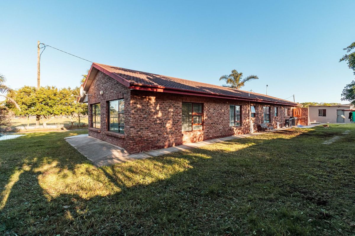 A view of the rear exterior of the brick-faced small holding dwelling, featuring a concrete patio area and surrounding garden space.
