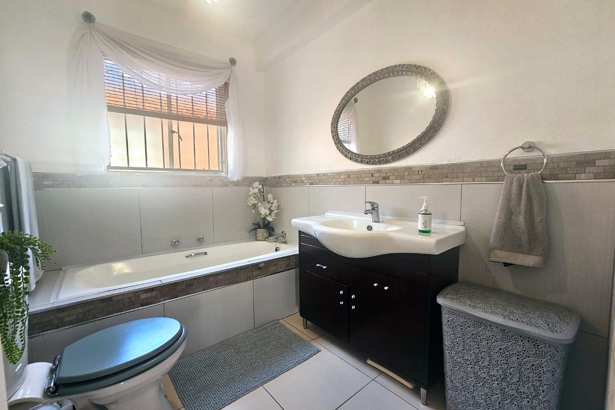 A functional bathroom featuring a built-in bathtub, a vanity cabinet with a basin, and tiled wall accents.