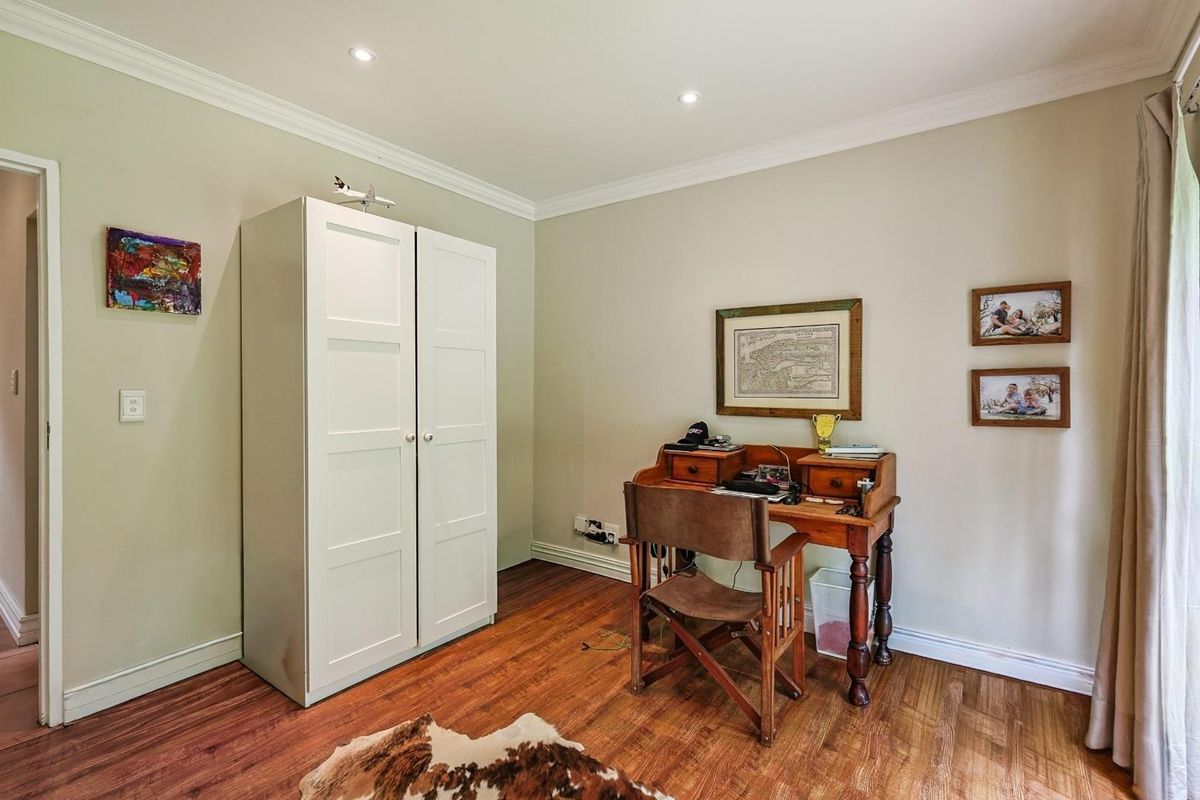 A well-maintained bedroom featuring warm wood-look flooring, recessed ceiling lighting, and crown molding, providing a comfortable and functional living space.