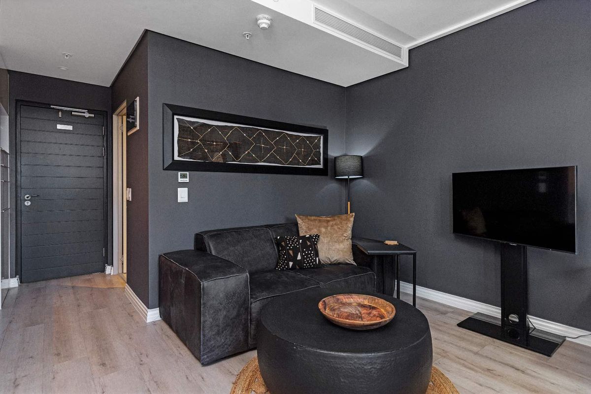 A modern, well-maintained living room featuring dark charcoal walls, light wood-look laminate flooring, and integrated ducted air conditioning.