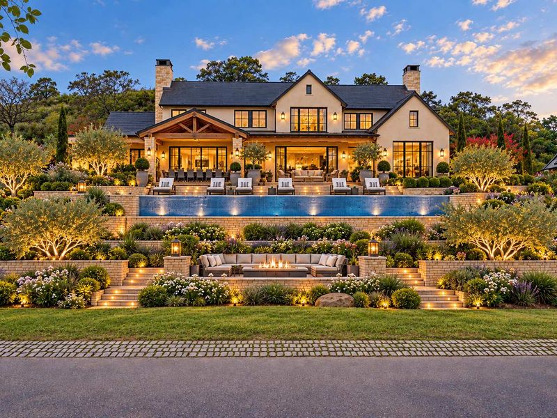 A stunning rear elevation featuring a multi-tiered landscaped garden, an infinity-edge swimming pool, and a sophisticated outdoor entertainment area with a built-in fire pit.