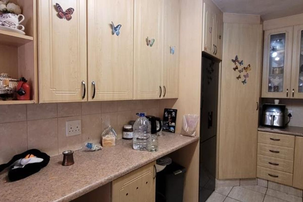A functional kitchen featuring light wood-tone cabinetry, tiled backsplash, and ample counter space, offering a practical layout for daily meal preparation.