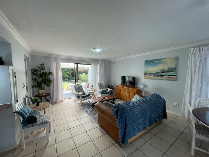Spacious open-plan living area featuring neutral tiled flooring and large sliding glass doors that provide direct access to the outdoor patio.