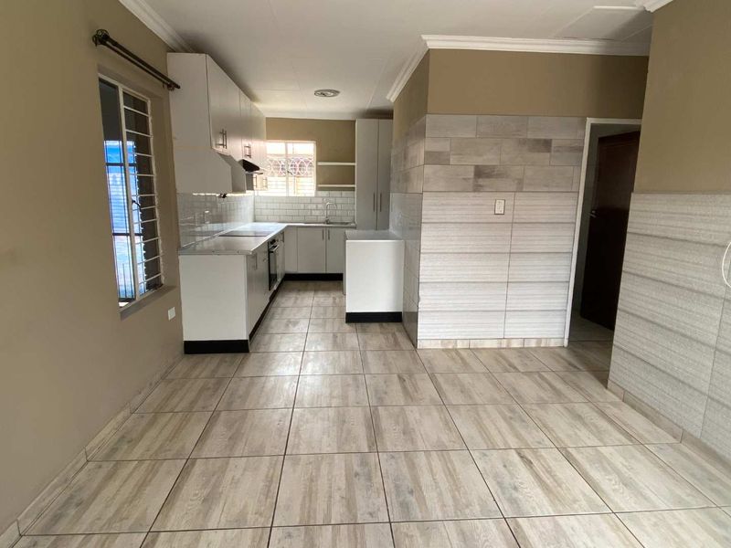 A clean, modern kitchen featuring white cabinetry, tiled splashbacks, and wood-look floor tiles, offering a functional and bright workspace.