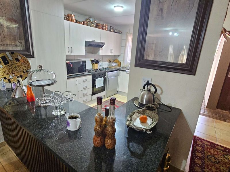 A functional kitchen featuring granite countertops, built-in cabinetry, an integrated dishwasher, and a built-in oven with an extractor fan.