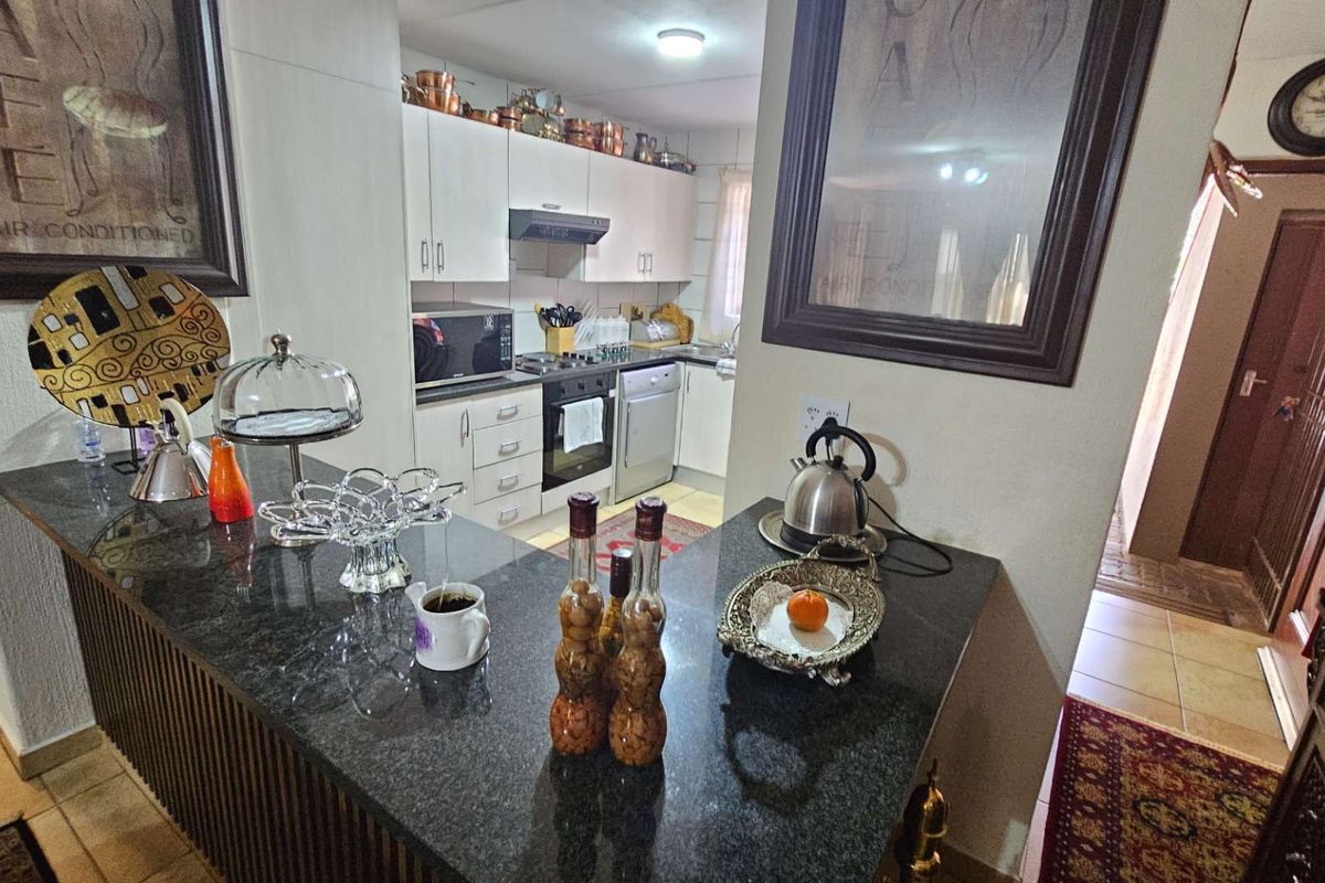 A functional kitchen featuring granite countertops, built-in cabinetry, an integrated dishwasher, and a built-in oven with an extractor fan.