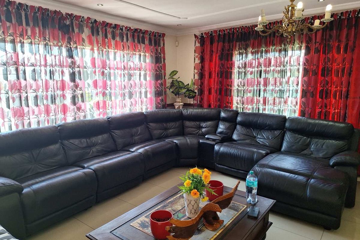 A spacious living room featuring tiled flooring, recessed downlighting, and decorative cornicing, providing a comfortable and functional area for relaxation.
