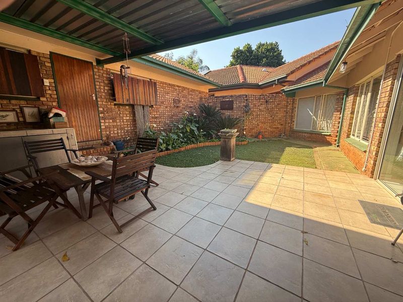 A covered patio area featuring tiled flooring, brick walls, and direct access to a small rear garden space.